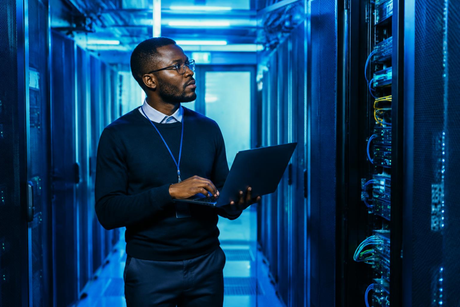 Intelli-Sys engineer with a laptop between data-centre server racks